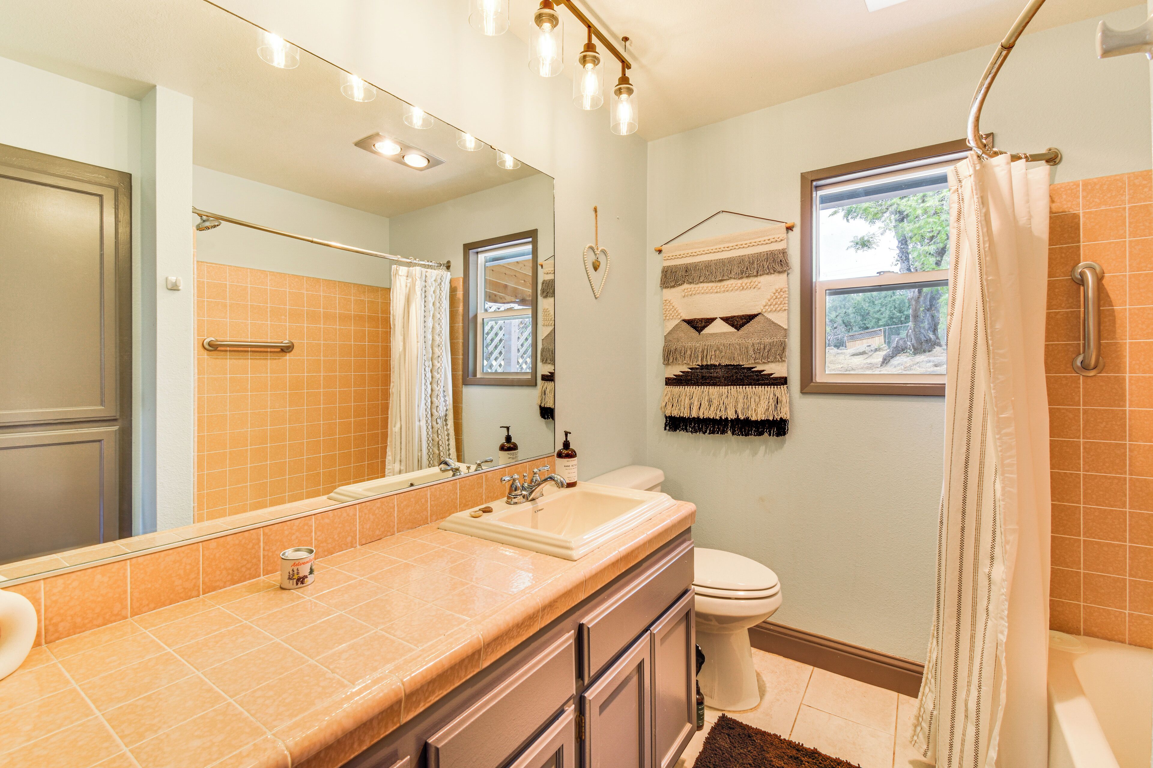 A bathroom with a large mirror, a sink, a toilet, and a shower area.