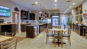 A restaurant with a counter, seating area, and a television displaying a golf course. - Savannah Lakes Village Home: Golf & Hike! (McCormick)