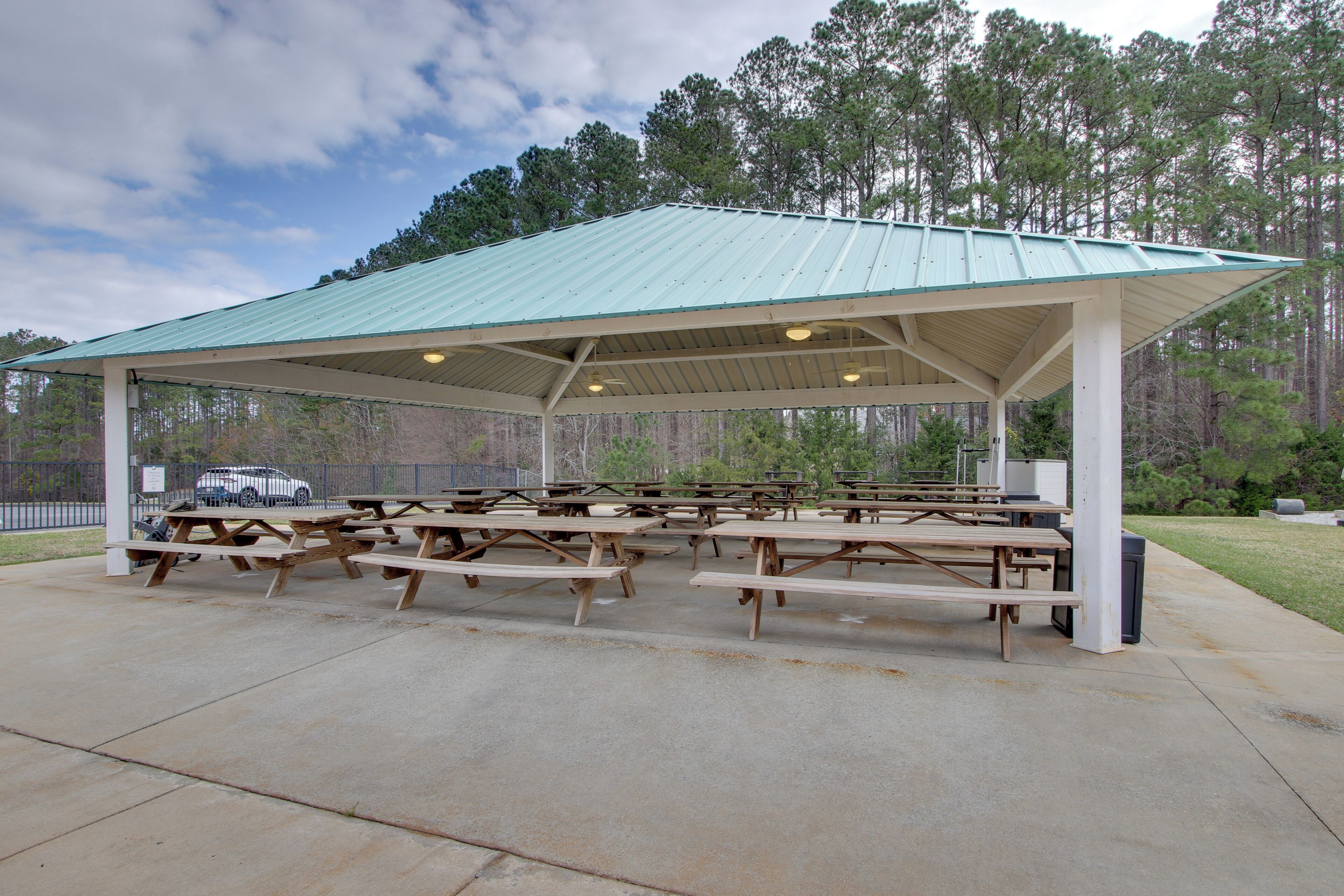 A covered picnic area with multiple picnic tables and a metal roof.