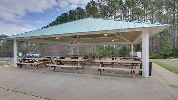 A covered picnic area with multiple picnic tables and a metal roof.
