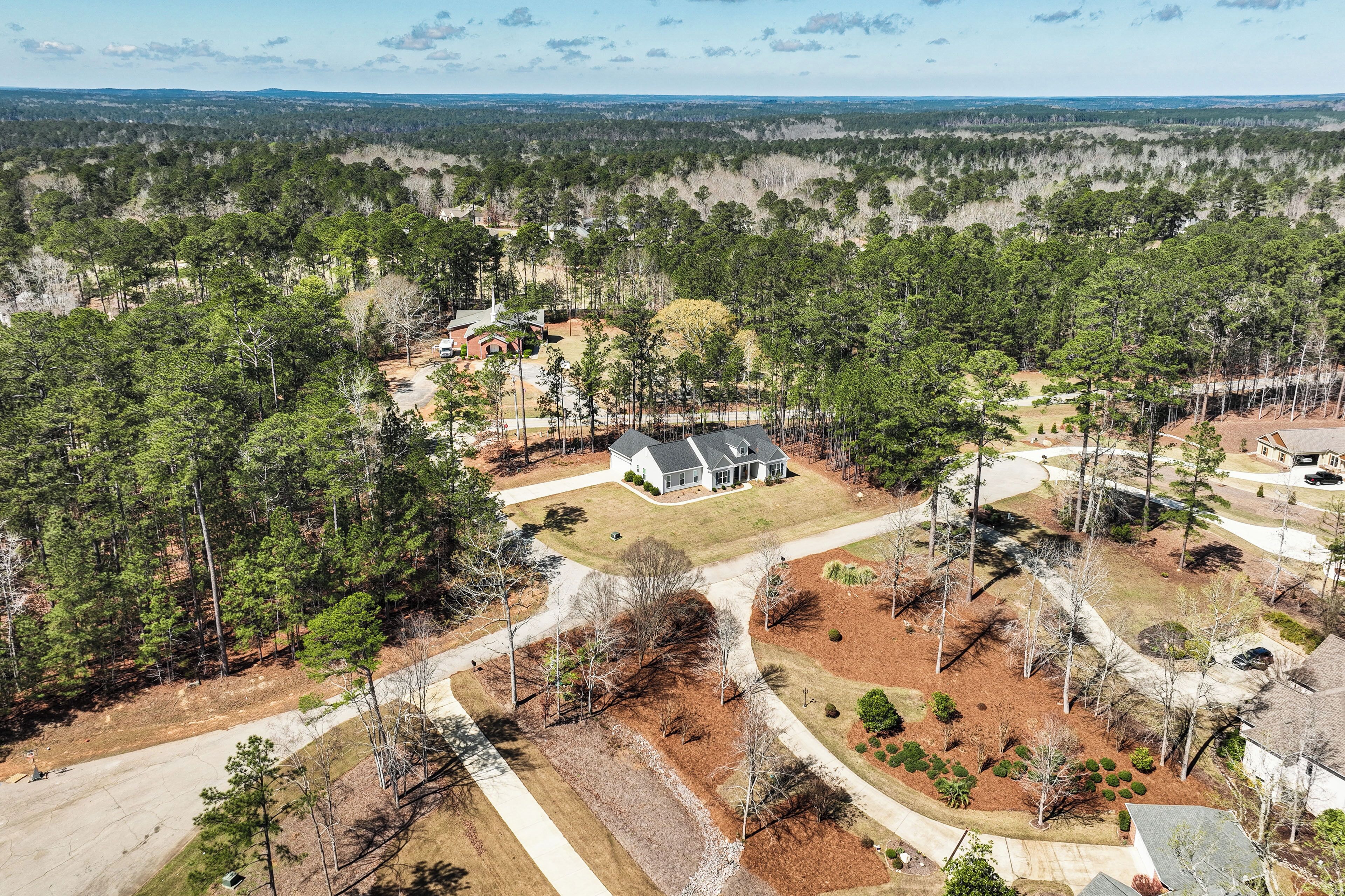 An aerial view of a residential area with a house surrounded by dense forest.
