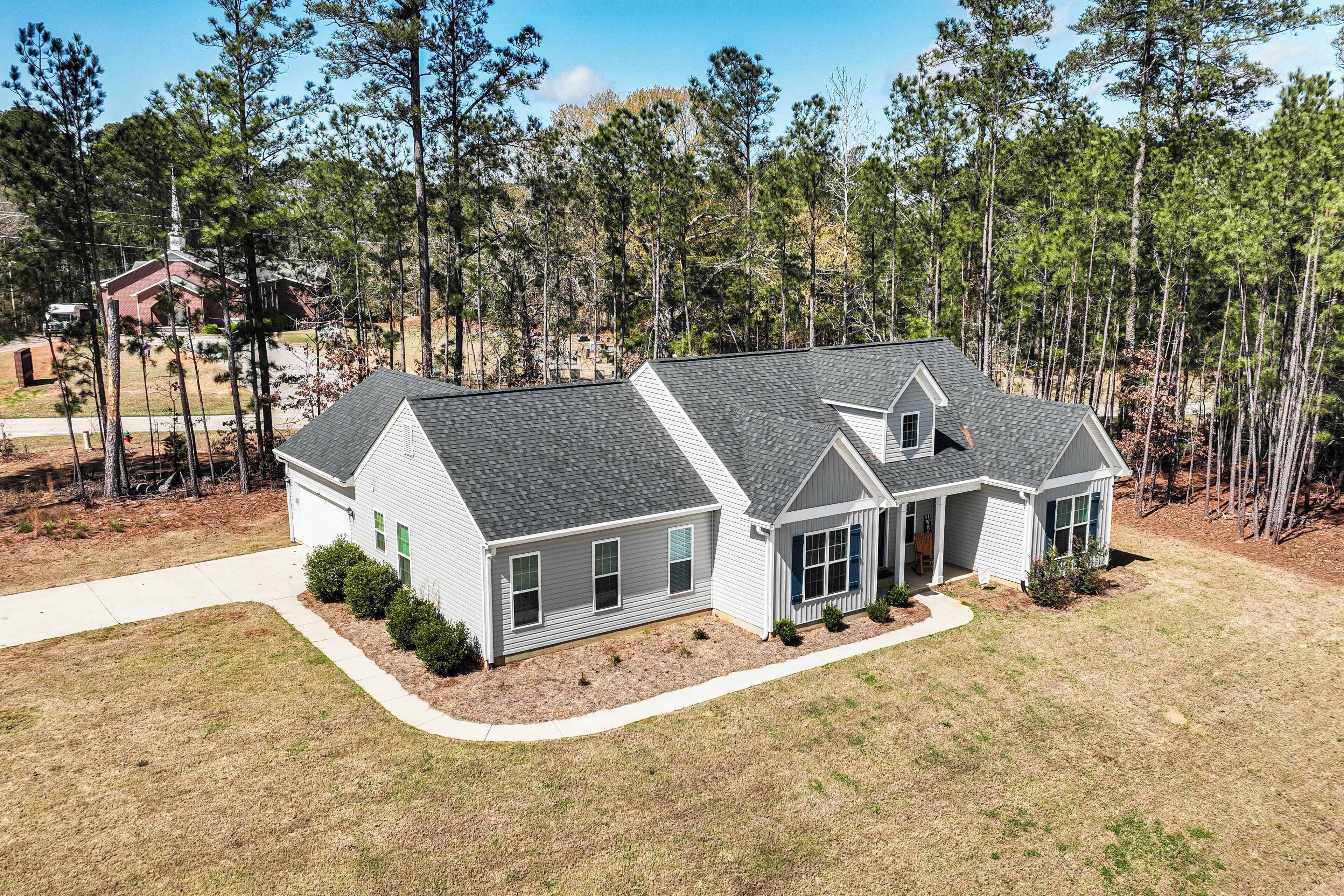 A two-story house with a grey roof, white siding, and a front porch.
