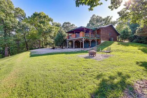 A rustic cabin with a covered porch and a fire pit in the yard.