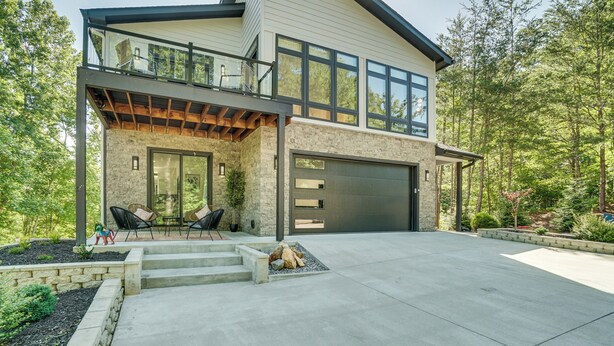 A modern two-story house with a large garage, a covered patio with outdoor furniture, and a stone facade. - Game Room, Fire Pit Free Pickleball & Tennis (Helen)