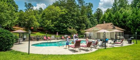 A backyard with a swimming pool, lounge chairs, and a covered patio area.