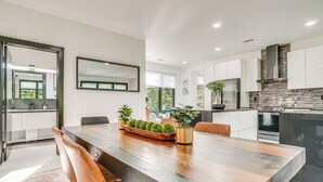 A modern kitchen with white cabinets, a large wooden dining table, and a built-in stove. - Game Room, Fire Pit Free Pickleball & Tennis (Helen)