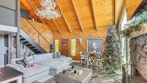 Ein geräumiger Wohnbereich mit hoher Holzbalkendecke, Kamin, Weihnachtsbaum und Essbereich.