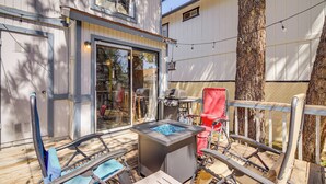 Una terraza con mobiliario exterior, una chimenea y un gran árbol.