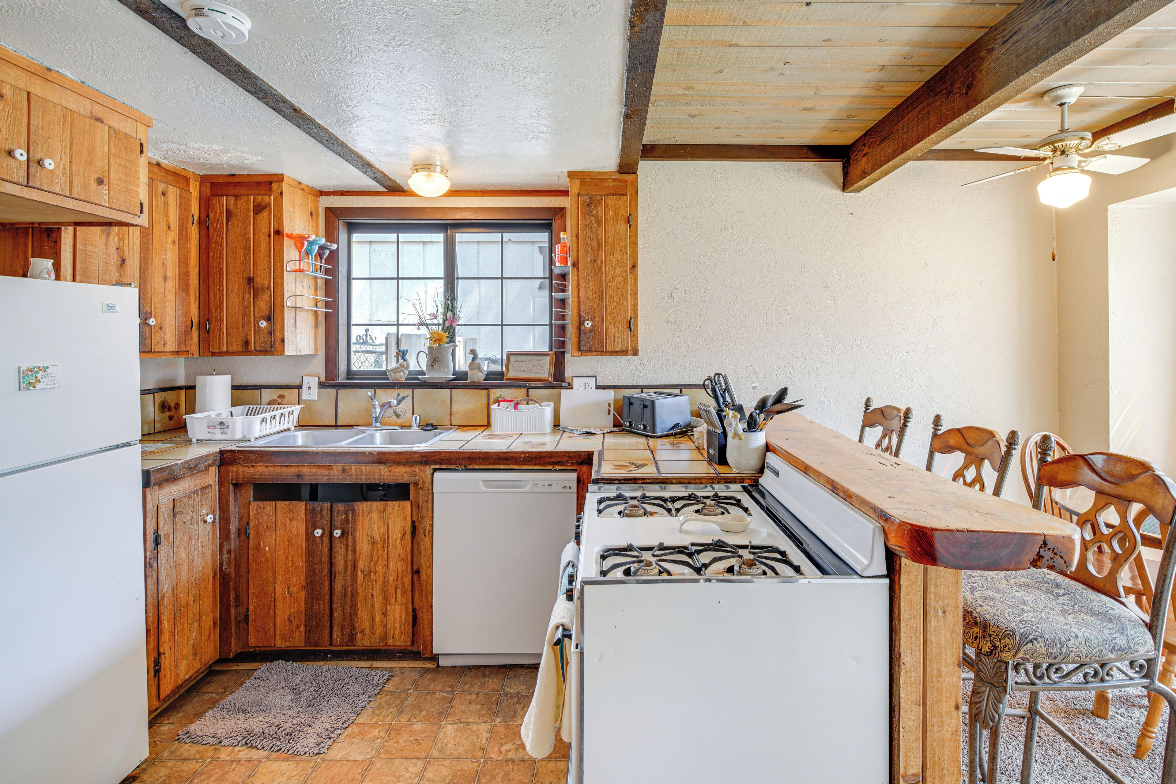 A kitchen with wooden cabinets, a stove, a sink, and a window.