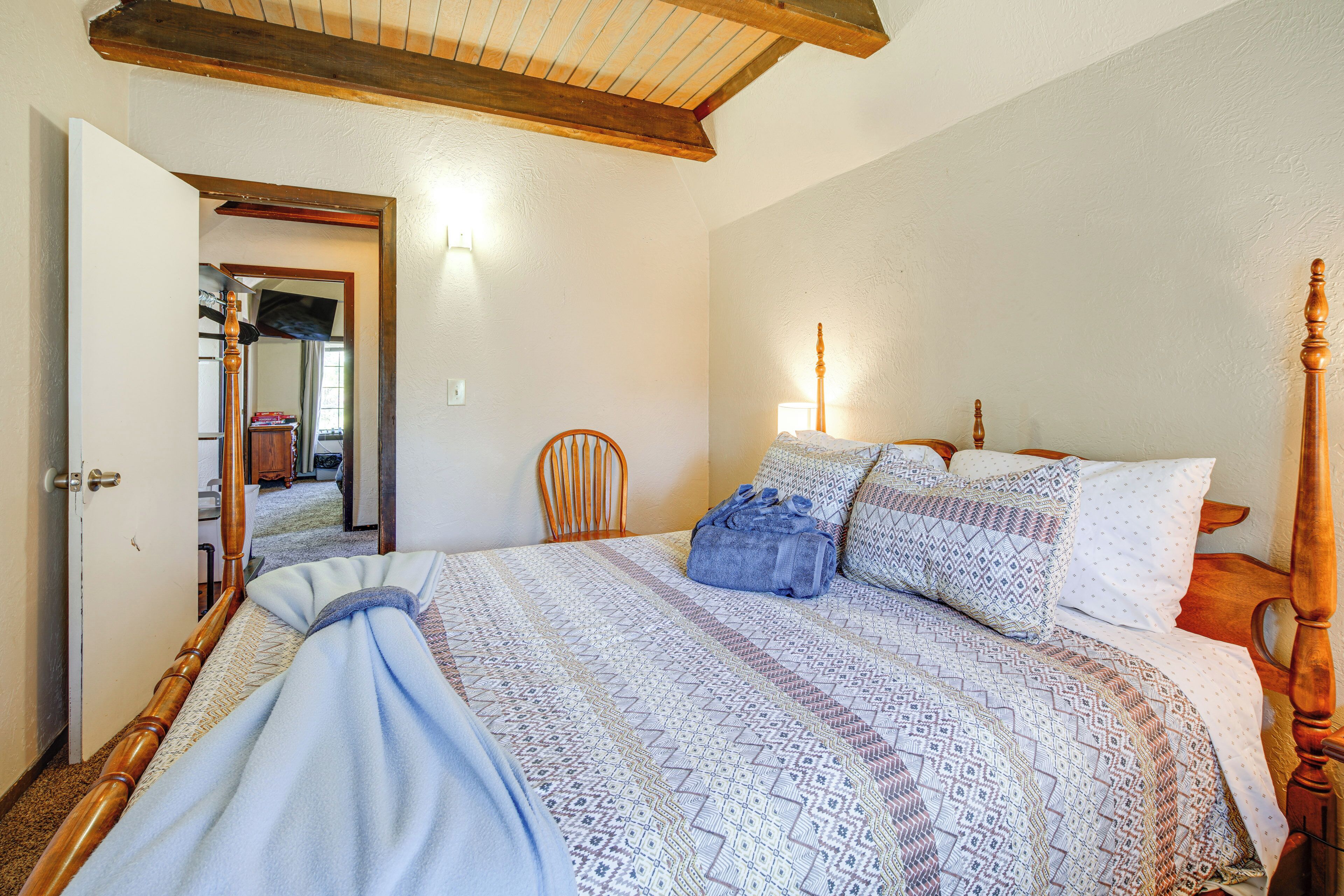 Un dormitorio con estructura de cama de madera, ropa de cama estampada y una silla de madera.