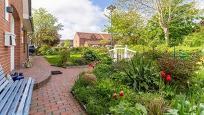A garden pathway leading to a building with a brick facade and a bench. - Ferienhaus mit Sauna in St.Peter-Ording (St. Peter-Ording)