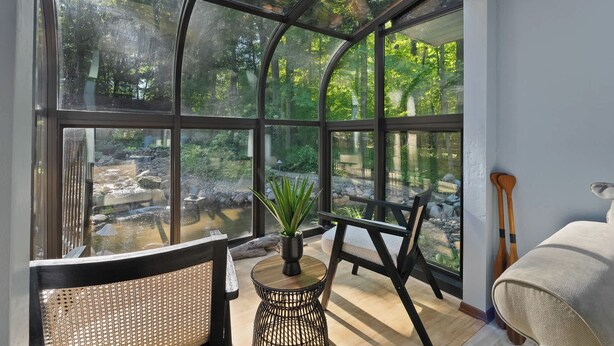 A conservatory with a view of a natural landscape, including a waterfall and greenery. - Waterfront Bayview Bliss Bungalow (Brussels)