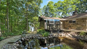 A house with a glass conservatory, a pond, and a stone pathway. - Waterfront Bayview Bliss Bungalow (Brussels)