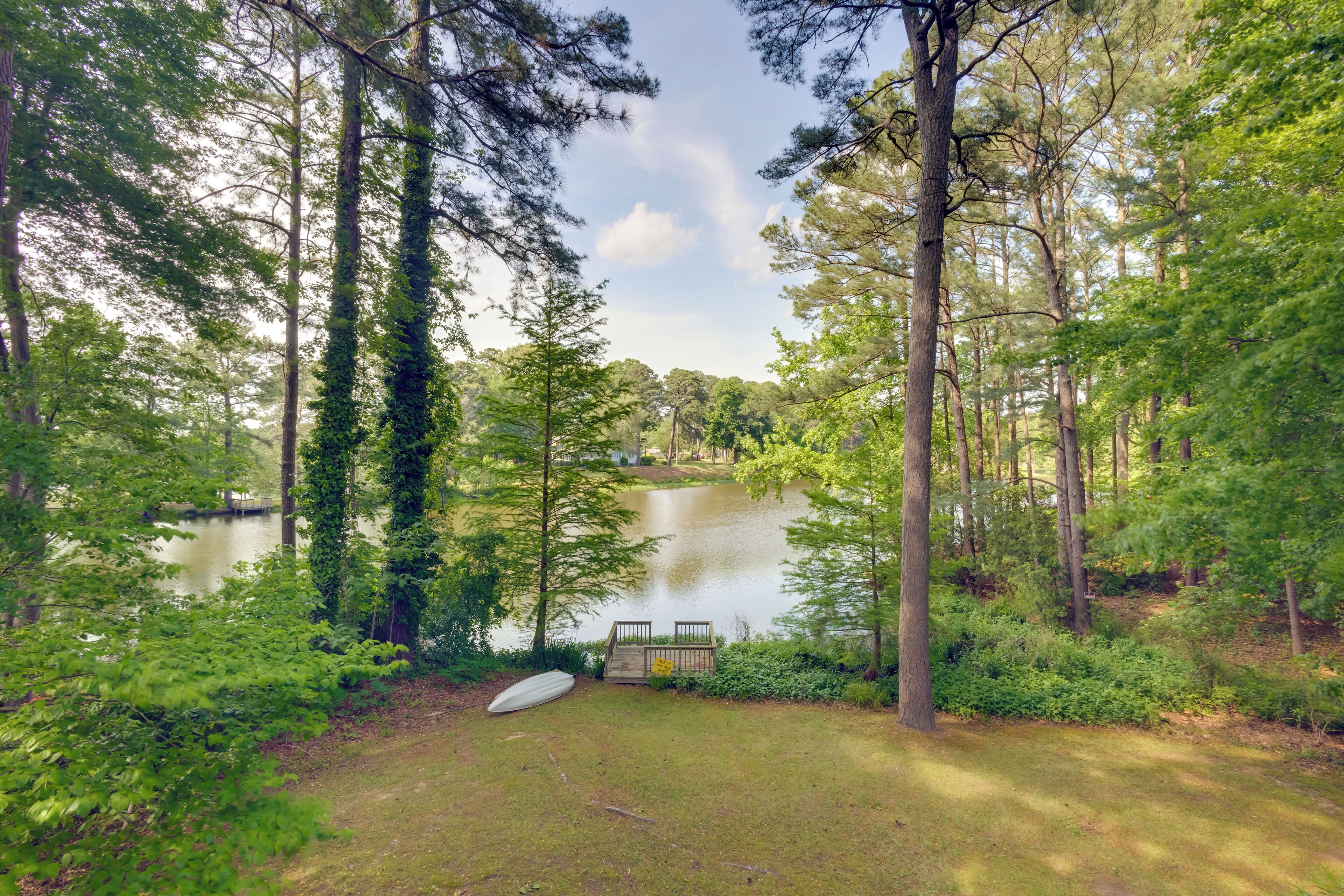 A serene lakeside setting with a wooden dock and a boat.