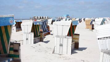 Des cabanes de plage dotées d’auvents à rayures et une plage de sable.