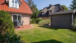 Een huis met een rode pannendak, een stenen gevel en een verzorgd gazon.