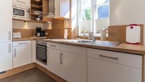Een moderne keuken met ingebouwde apparatuur, een groot raam en uitzicht op de omgeving.