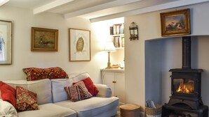 Ein gemütliches Wohnzimmer mit einer Couch, gemusterten Kissen, einem Kamin und einem Bücherregal.