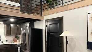 A modern kitchen with dark cabinets, a stainless steel refrigerator, and a wooden countertop. - DTSF Historic Phillips Loft in the heart of Downtown Sioux Falls (Sioux Falls)