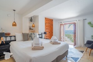 A bedroom with a large bed, two towels, a desk with a lamp, a chair, and a view through an open door. - CostaBlancaDreams - Casa Lynn in Javea (Javea / Xàbia)