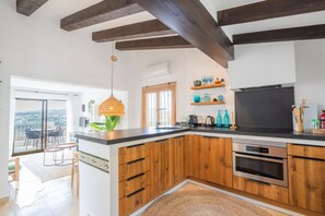 Une cuisine moderne avec des armoires en bois, un comptoir noir et un four encastré. Une grande fenêtre offre une vue sur l’extérieur.