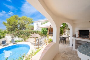 A swimming pool with lounge chairs, a barbecue area, and a view of a building in the background. - CostaBlancaDreams - Casa Lynn in Javea (Javea / Xàbia)