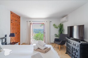 Une chambre d’hôtel comprenant un lit, une télévision, un bureau avec une lampe, une chaise et une vue sur l’extérieur.