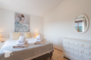 Une chambre d’hôtel avec un grand lit, une commode, un tableau au mur et un miroir.