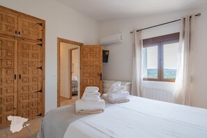 Een hotelkamer met een groot bed, een houten kledingkast, een raam met gordijnen en uitzicht op de omgeving.