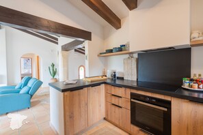 A modern kitchen with wooden cabinets, a black countertop, and a built-in oven. - CostaBlancaDreams - Casa Lynn in Javea (Javea / Xàbia)