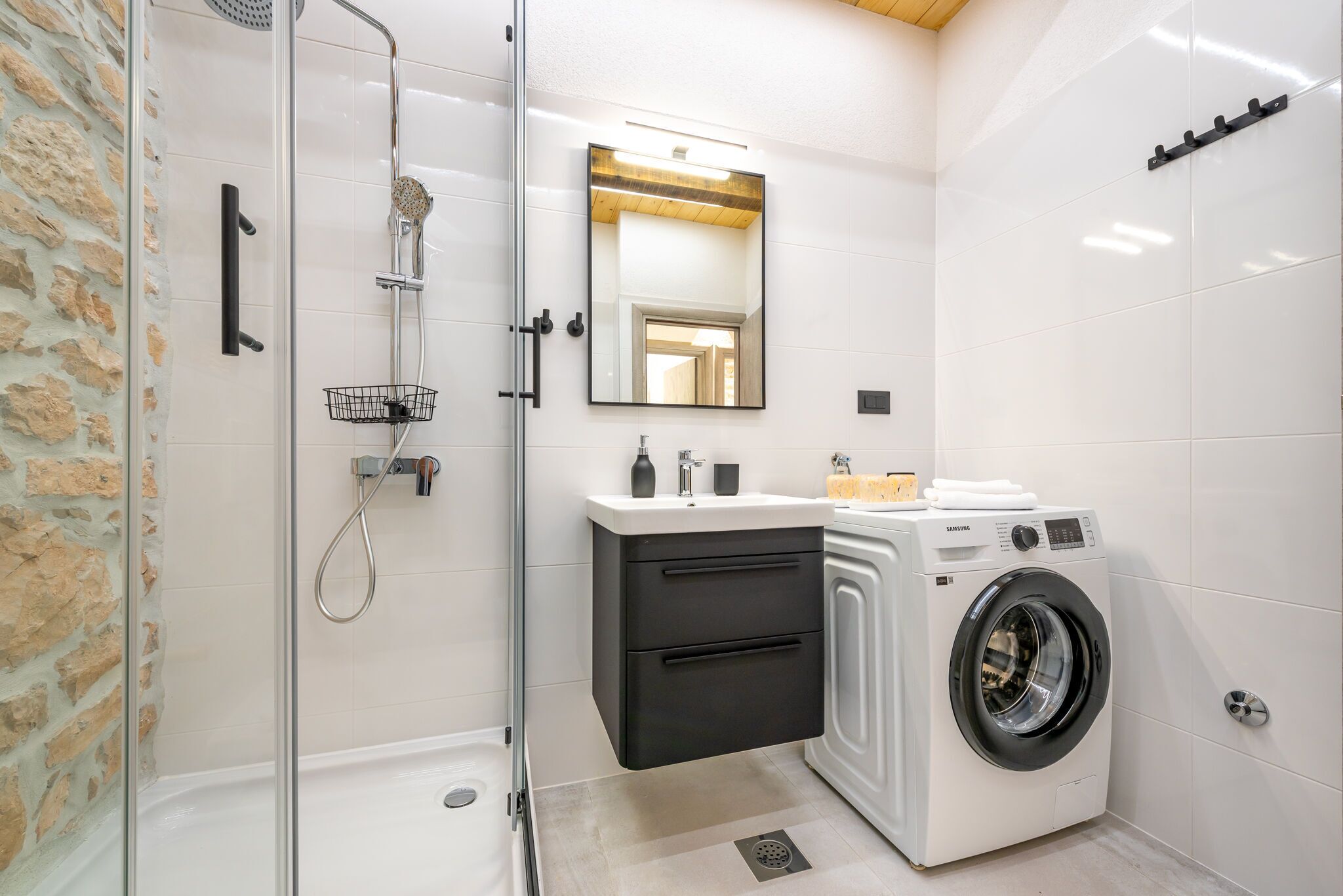 Une salle de bain moderne avec une douche à parois de verre, un lave-linge encastré et un miroir au-dessus du lavabo.