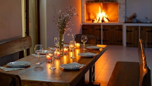 A dining table set for a meal with candles, a vase of flowers, and a fireplace in the background. - Villa Kole (Konjevrate)