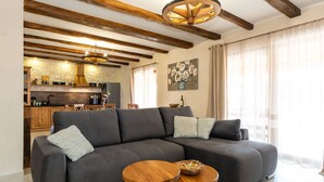 A modern living room with a sectional sofa, two wooden side tables, and a rustic ceiling with exposed beams. - Villa Kole (Konjevrate)