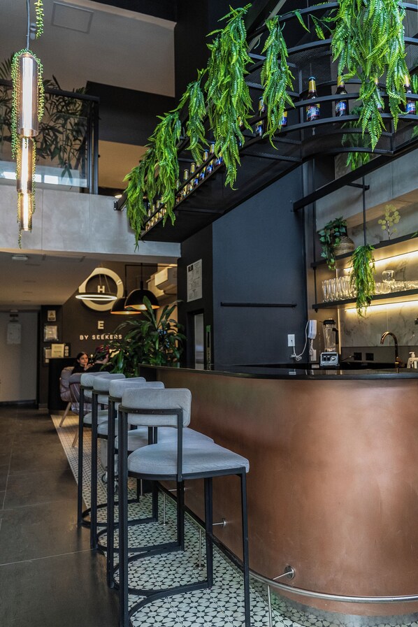 A modern bar area with seating, a counter, and hanging plants.