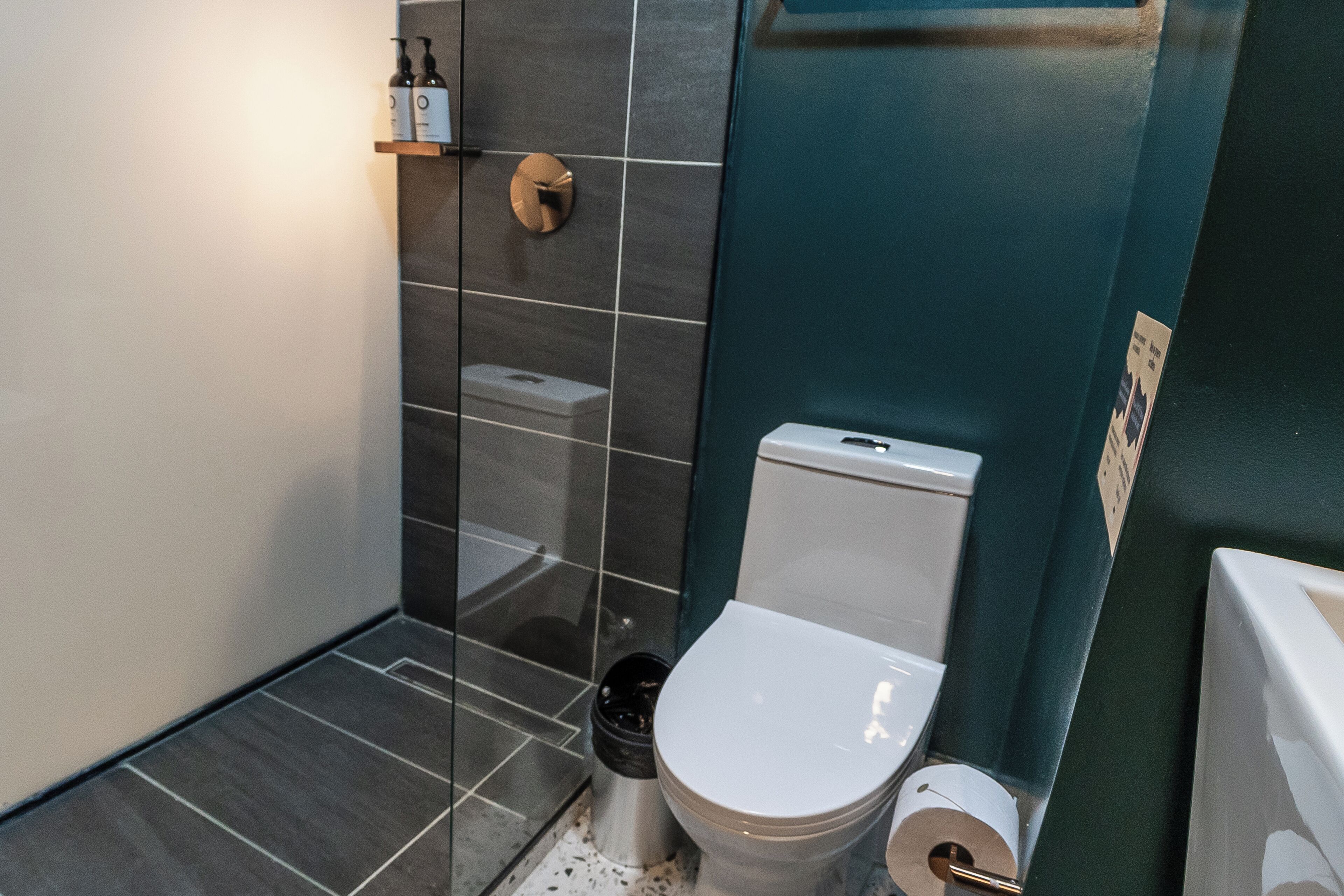 Ein modernes Badezimmer mit Toilette, Mülleimer und Ablagefläche für Pflegeprodukte.