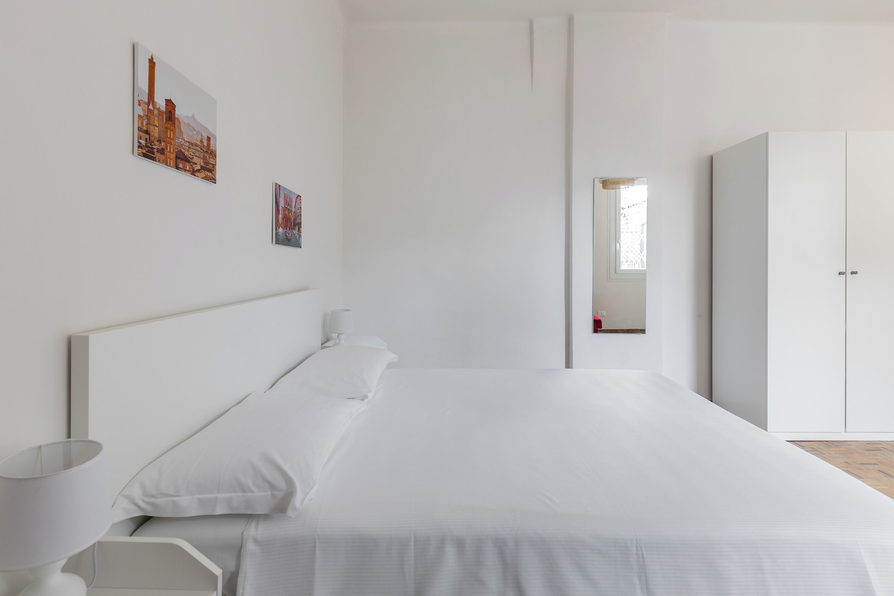 Une chambre à coucher au style minimaliste, avec un grand lit, une table de chevet, une lampe et une armoire.
