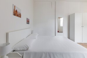 A minimalist bedroom with a large bed, a bedside table, a lamp, and a wardrobe. - Alessandrini Apartment alla Finestrella by Wonderful Italy (Bologna)