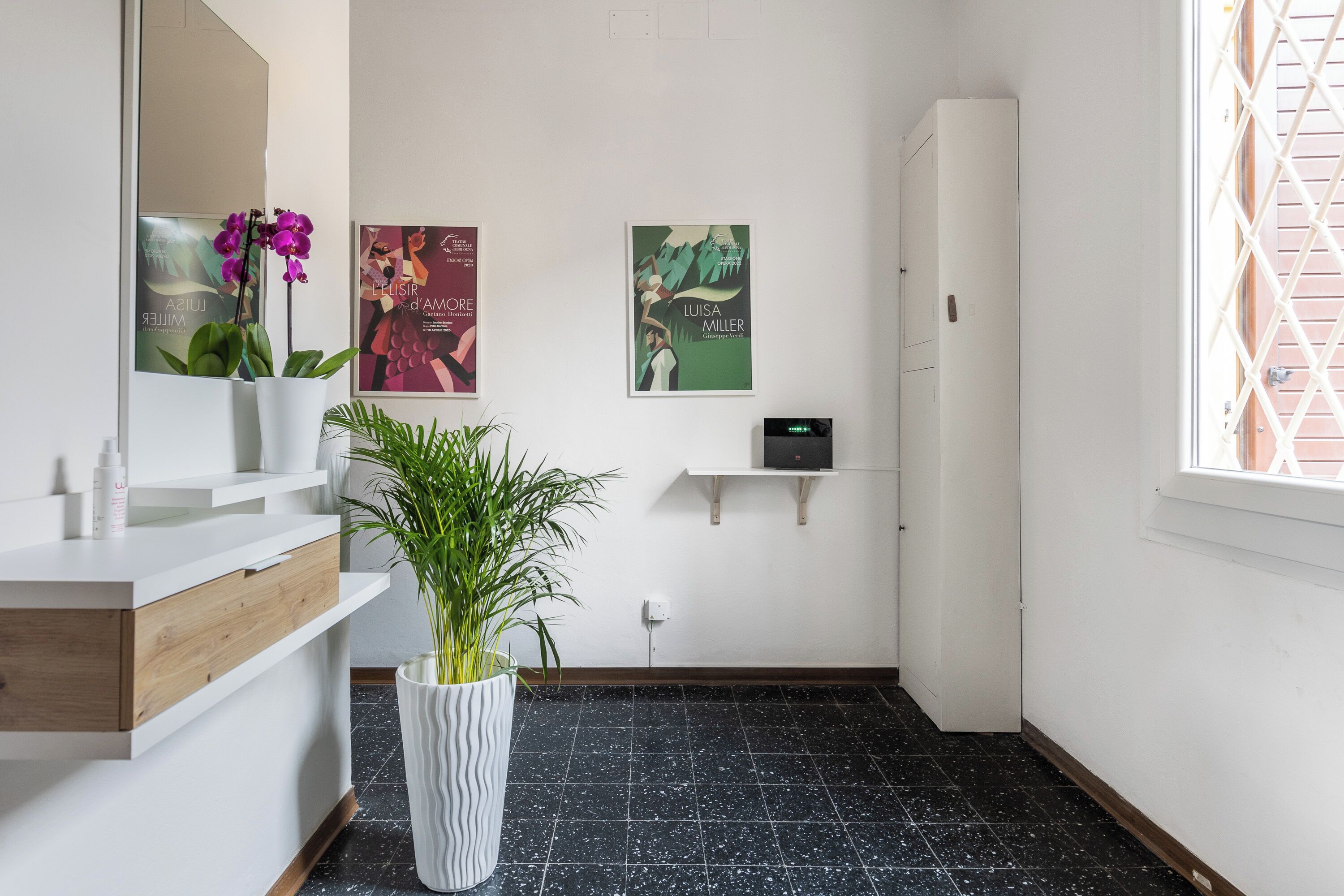 Een moderne badkamer met een witte wastafel, een potplant en kunst aan de muur.