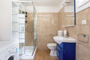 A modern bathroom with a glass-enclosed shower, a toilet, and a sink with a mirror above. - Alessandrini Apartment alla Finestrella by Wonderful Italy (Bologna)