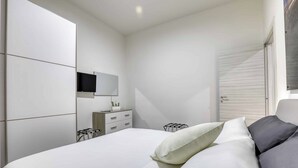 A modern bedroom with a large bed, a bedside table, a mirror, and a wardrobe. - Tourist Apartment Civitavecchia (Civitavecchia)