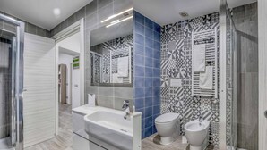 A modern bathroom with a large mirror, a sink, a toilet, and a bidet. - Tourist Apartment Civitavecchia (Civitavecchia)