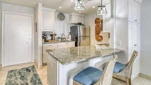 A modern kitchen with white cabinetry, a granite island, and a built-in refrigerator.