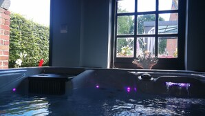 A hot tub with a view of a brick wall and a window.