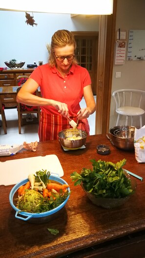 Une personne préparant des aliments dans une cuisine, avec un plan de travail en bois, un saladier et divers ingrédients.