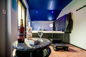 A bar area with a bottle of La Vauban Barley Style beer, two glasses, and a small bowl of snacks on a round table. - Gastronomique Table et Chambre D'hôte (Gommegnies)