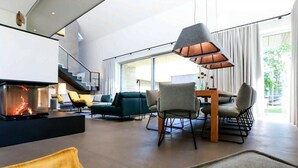A modern living room with a fireplace, comfortable seating, and a dining area.