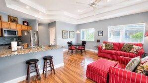 A spacious living area with a kitchen, a dining table, and a red-striped sofa.