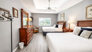 A bedroom with two beds, a dresser, a chair, a ceiling fan, and a window with blinds. - Right Direction Rentals 1 Bedroom Villa 8954 (Port St. Lucie)