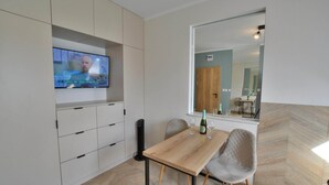 Una cocina moderna con televisor integrado, armarios de madera y una zona de comedor con mesa y sillas.