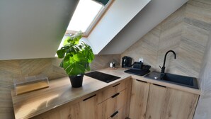 Una cocina moderna con tragaluz, armarios de madera, un lavamanos negro y una cafetera.
